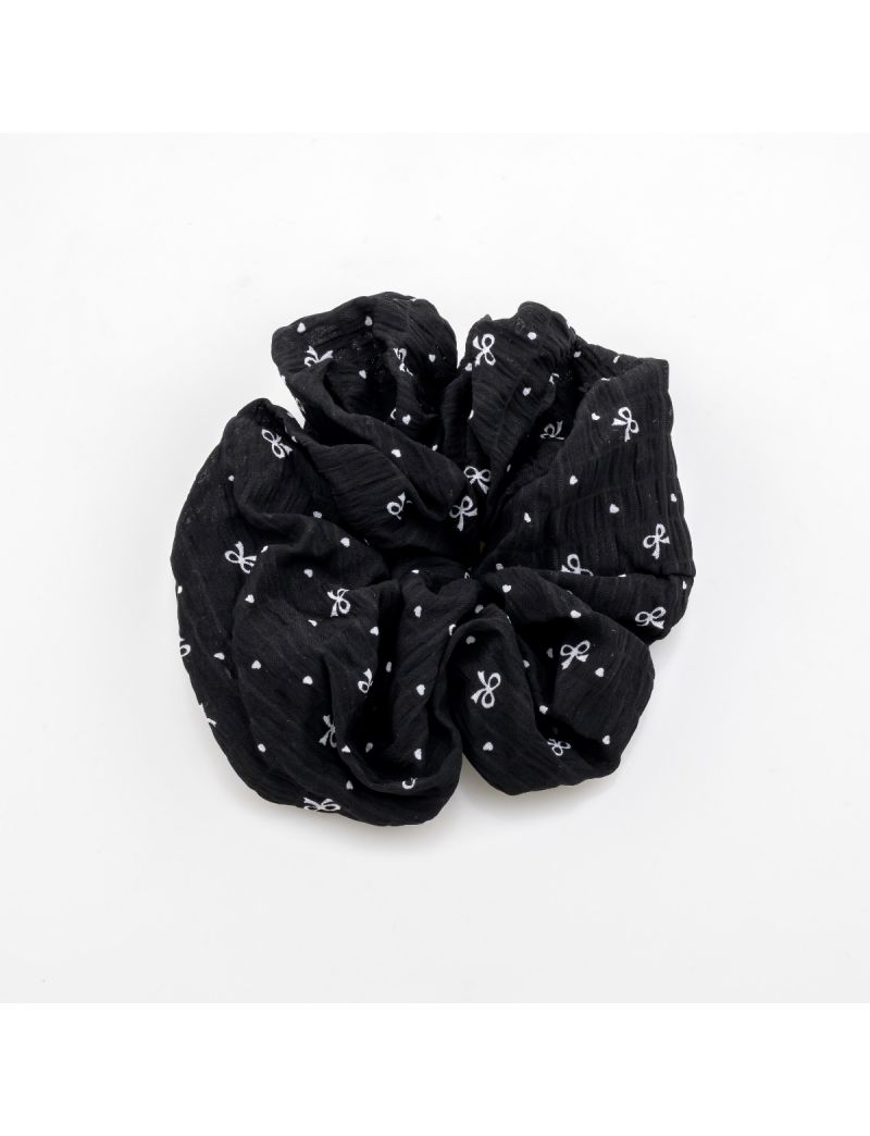 Υφασμάτινο scrunchie μαλλιών με ανάγλυφη υφή, διακοσμημένο με μικρούς φιόγκους και πουά, διαθέσιμο σε μαύρο και κρεμ χρώμα.